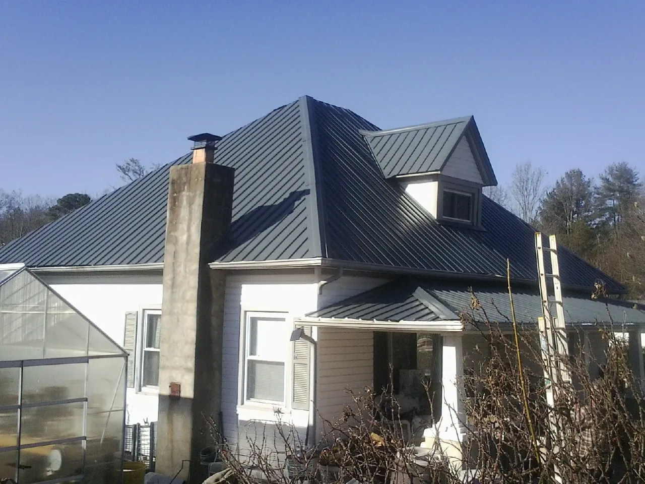 Dark blue standing seam metal roof on a white farmhouse with dormer — Slate & Tile Roof Repair by Roofing Brothers in Showell