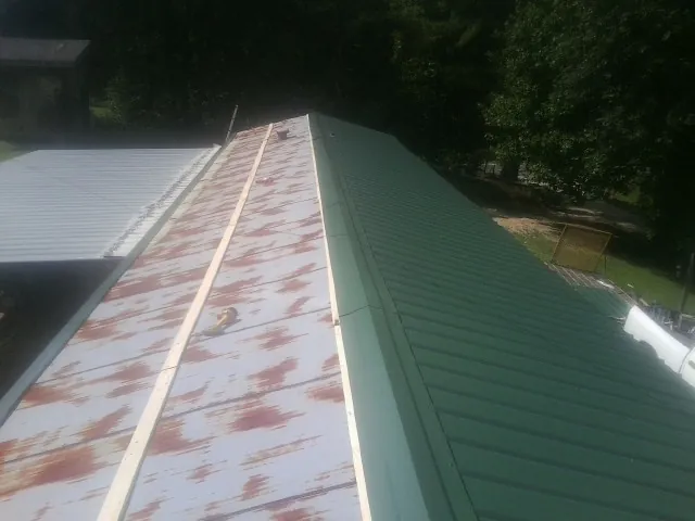 Old rusted panels beside newly installed green metal roofing — Wind Damage Roof Repair by Roofing Brothers in Showell