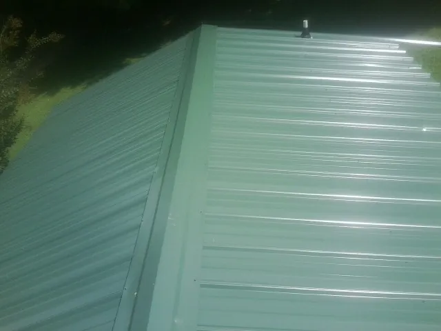 New green metal panels meeting at the ridge of a roof — Flat Roof Repair work by our crew in Showell