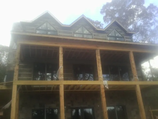 Dormers and porch framing on a large log home under construction — Roof Coating work by our crew in Showell