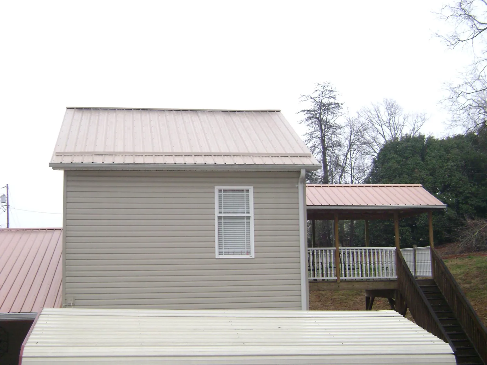 Tan metal roofs on a two story addition and attached porch, from a Roof Replacement job in Showell