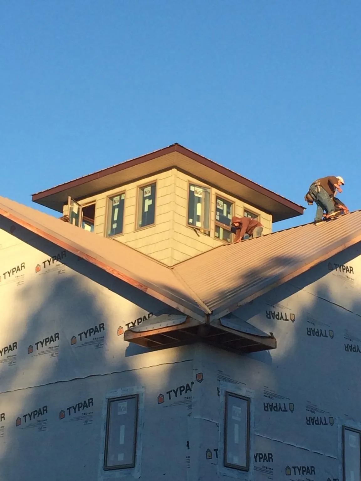 Roofers working around a rooftop cupola on a new metal roof at sunset — Roof Waterproofing in Showell by Roofing Brothers